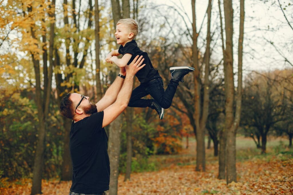 Father Lifting Up his young boy with ease in the outdoors